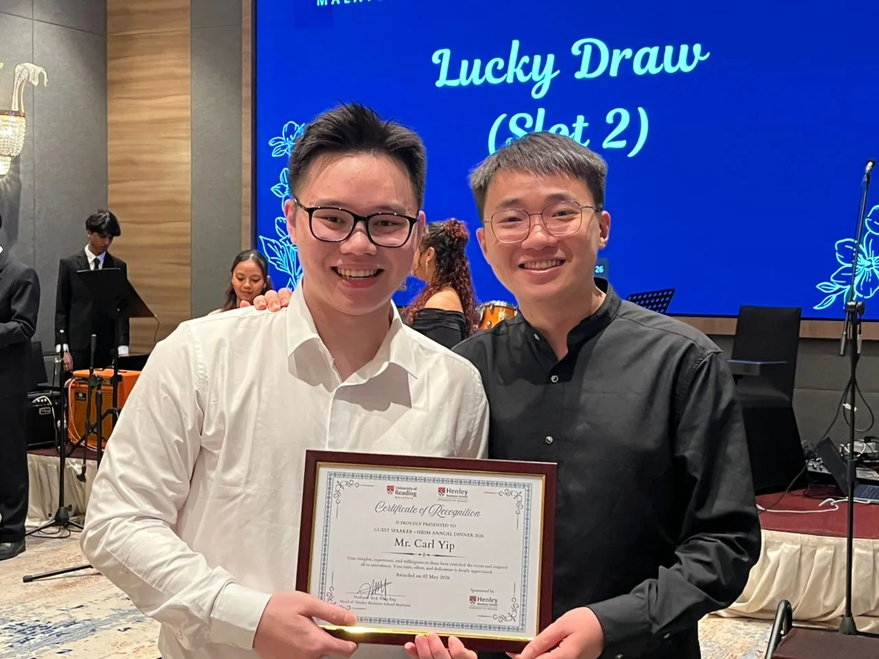 Carl Yip with Certificate of Recognition on stage at the lucky draw segment